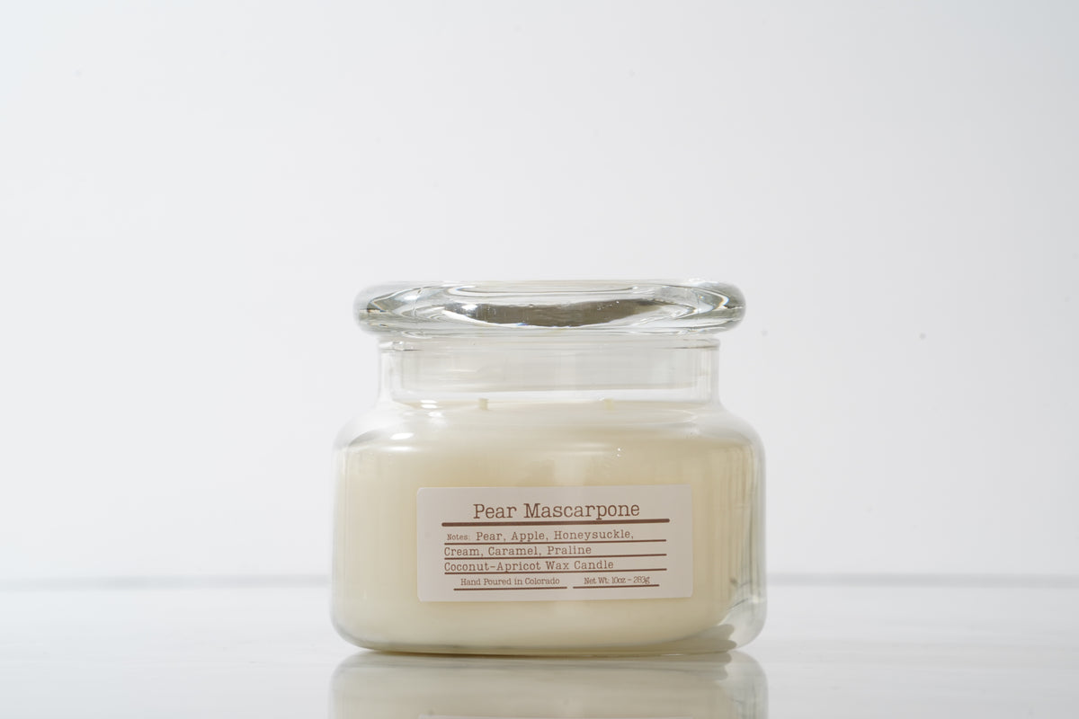 Glass jar candle labeled 'Pear Mascarpone' on a white background