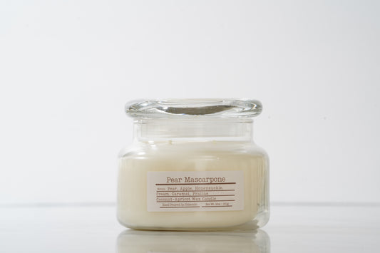 Glass jar candle labeled 'Pear Mascarpone' on a white background
